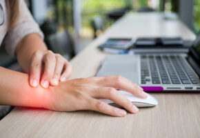 Closeup woman holding her wrist pain from using computer. Office syndrome hand pain by occupational disease.