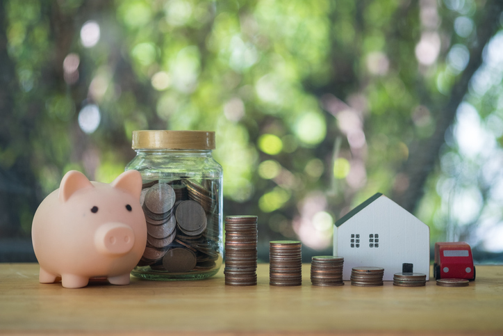 Money coins in glass bottles with a piggy bank, stock of coin, home and car with nature background. Insurance money savings, retirement planning and investment ideas