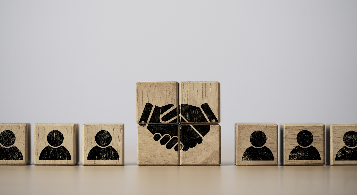 Hand shaking print screen on wooden block cube between human icon for business deal and agreement concept.
