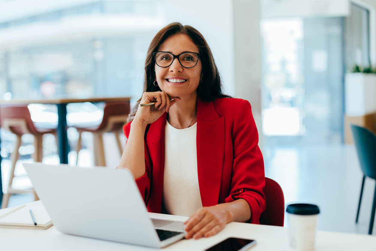 Confident businesswoman working on a laptop at a bright office desk